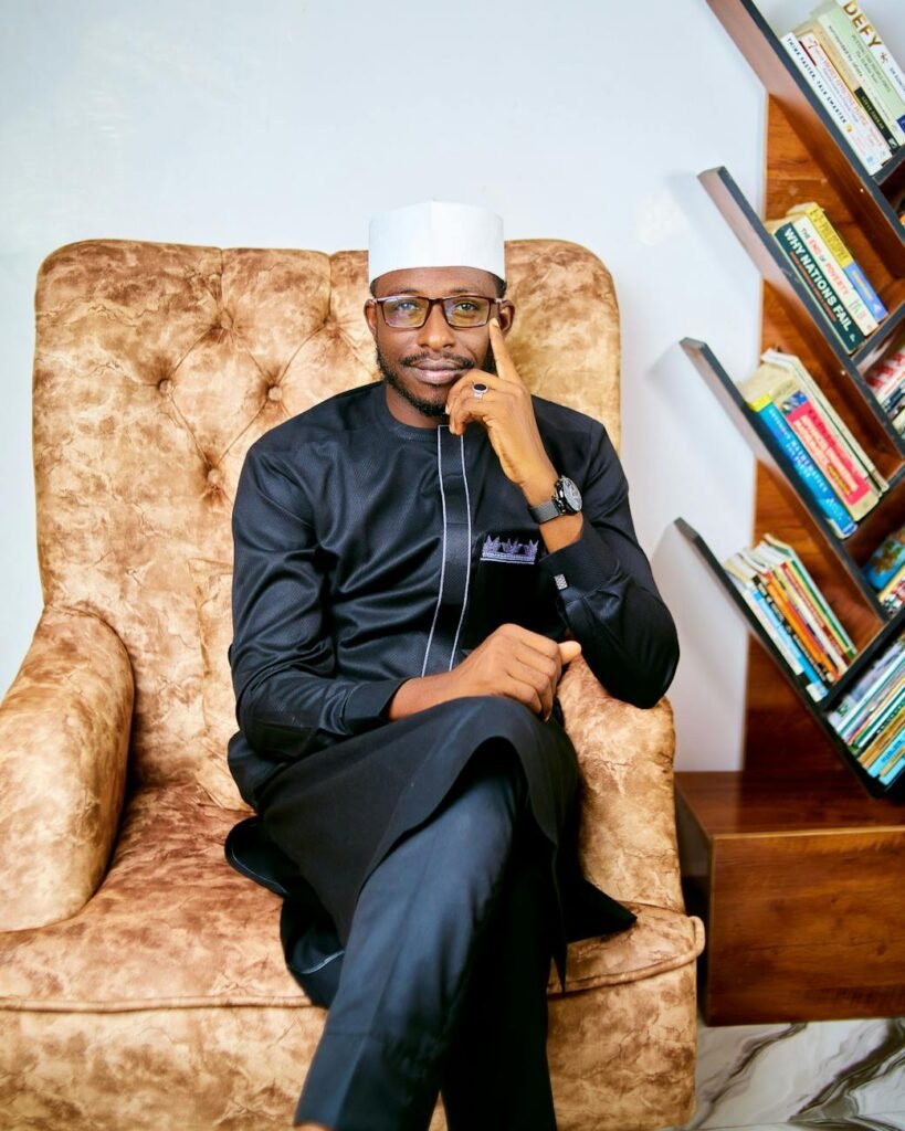confident man posing in armchair with bookshelf