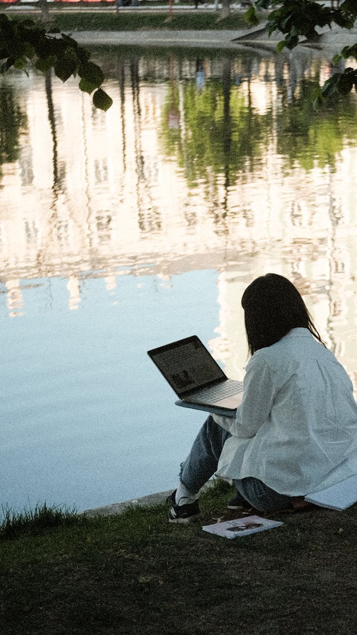 woman sitting and working on laptop at park
